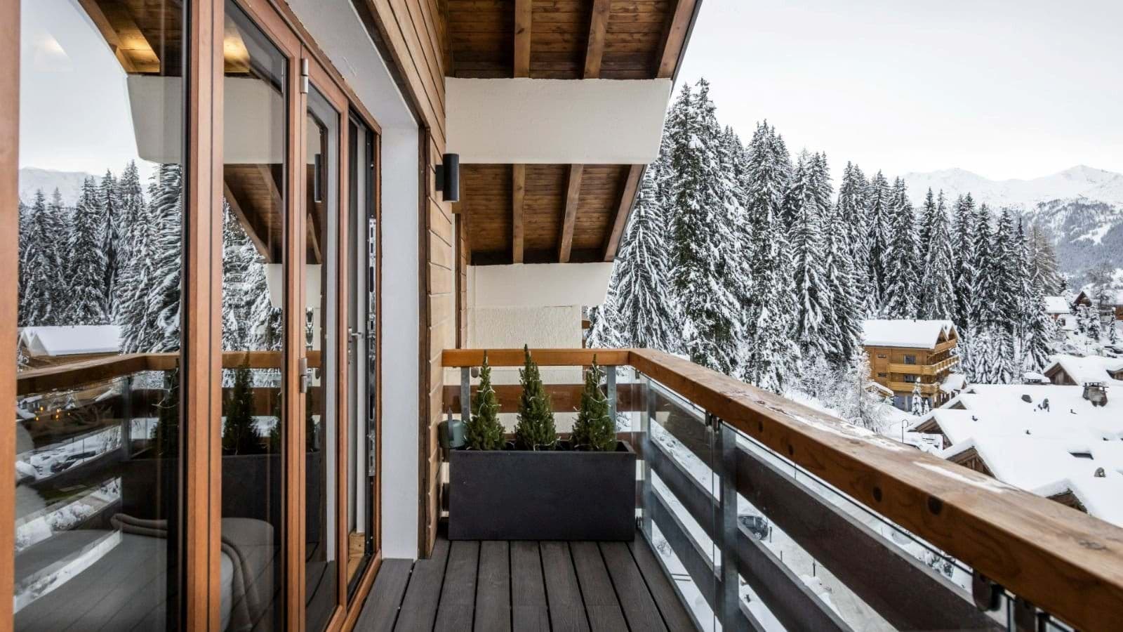 Private balcony with glass railings and snow-covered forest views