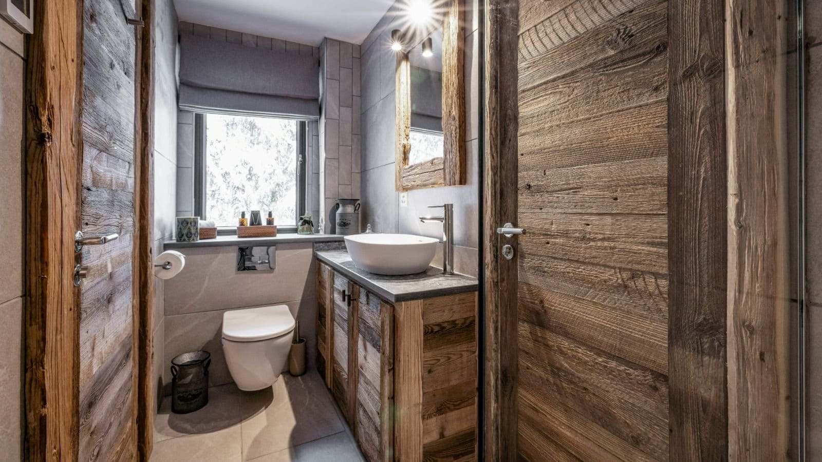 Bathroom featuring vessel sink, reclaimed wood cabinetry, and frosted window