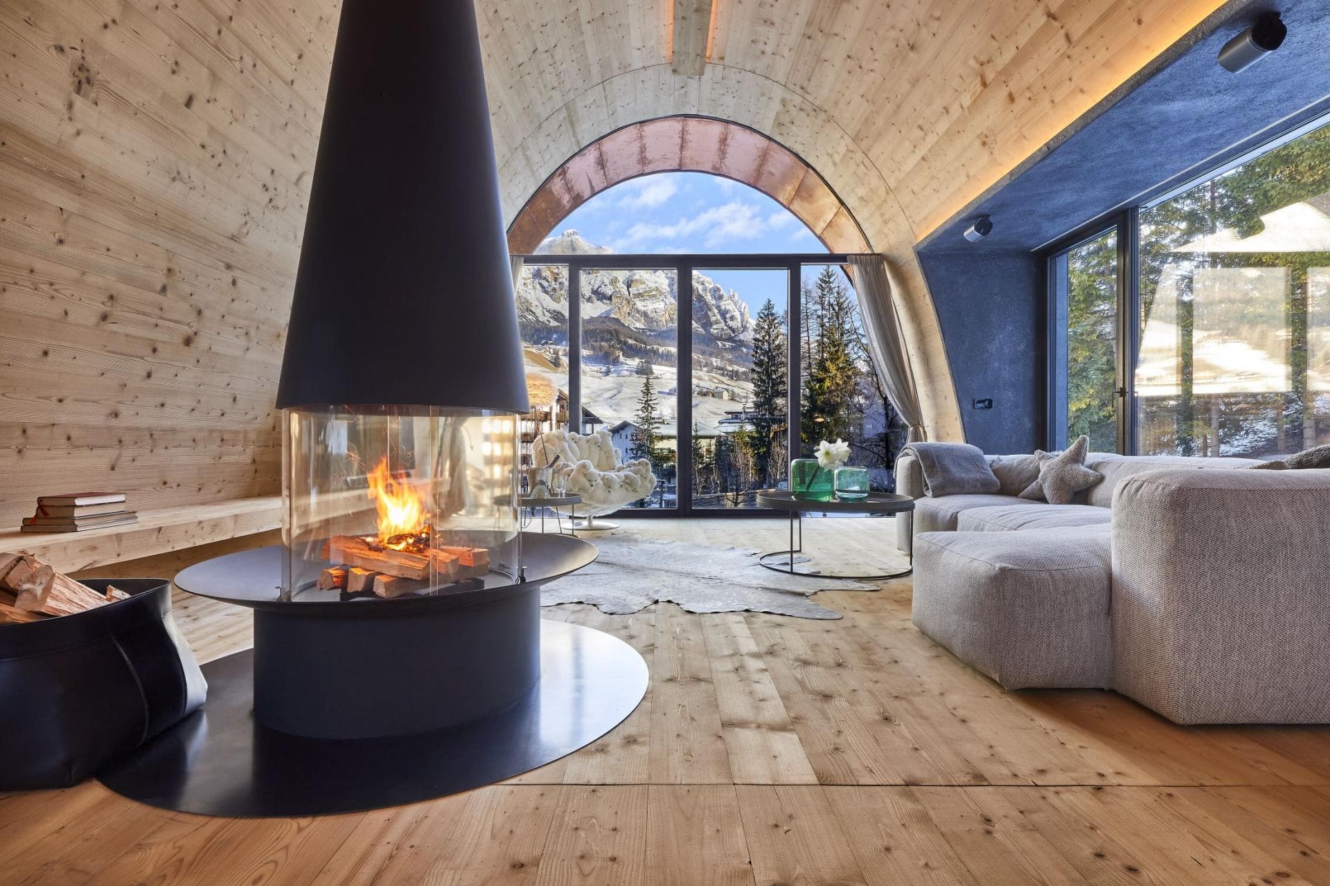 Living area with 360-degree fireplace and arched mountain views