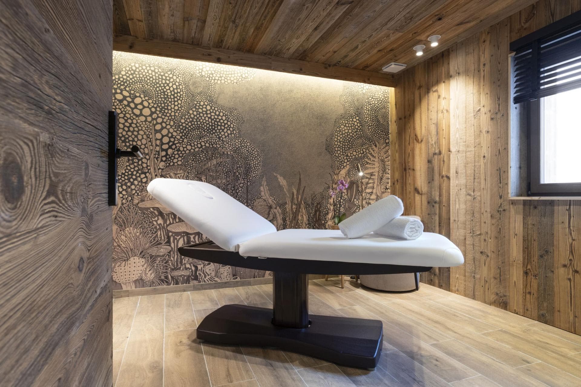 Private massage room with adjustable treatment table and wood-paneled walls