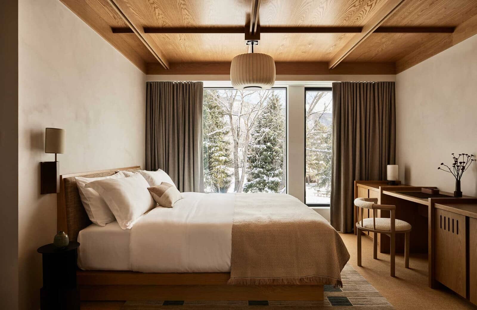 Primary bedroom with king bed, dedicated workspace, and snow-covered forest views