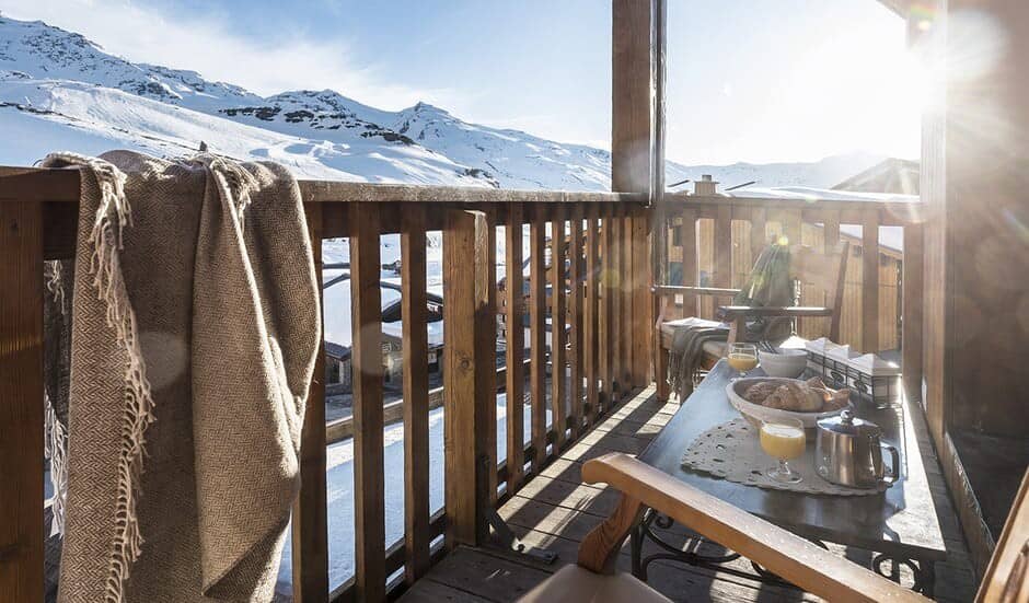 Wooden balcony with breakfast table and panoramic ski slope views