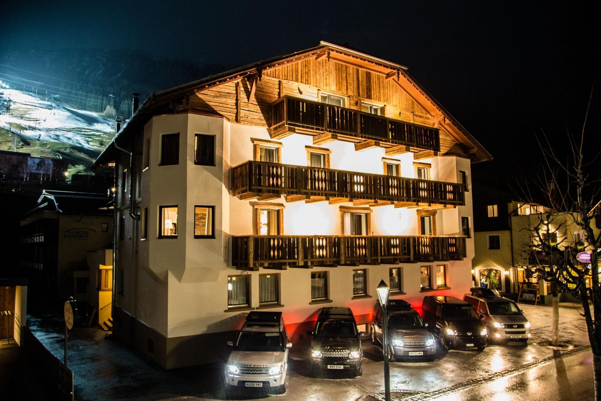 Chalet exterior at night with private parking and floodlit ski slope views