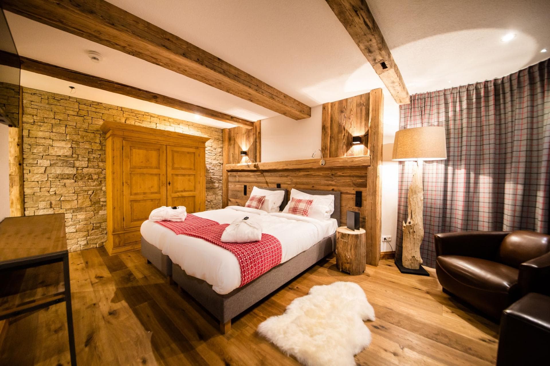 Guest bedroom with two twin beds, stone accent wall, and wood beams