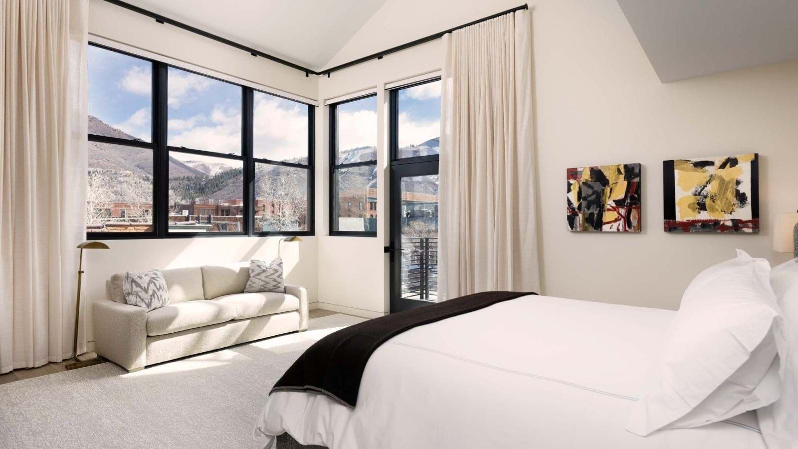 Primary bedroom with seating area, vaulted ceilings, and private balcony access