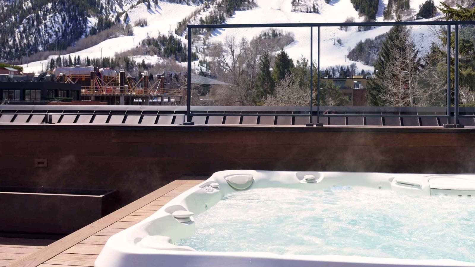 Rooftop hot tub with glass railing and ski slope views