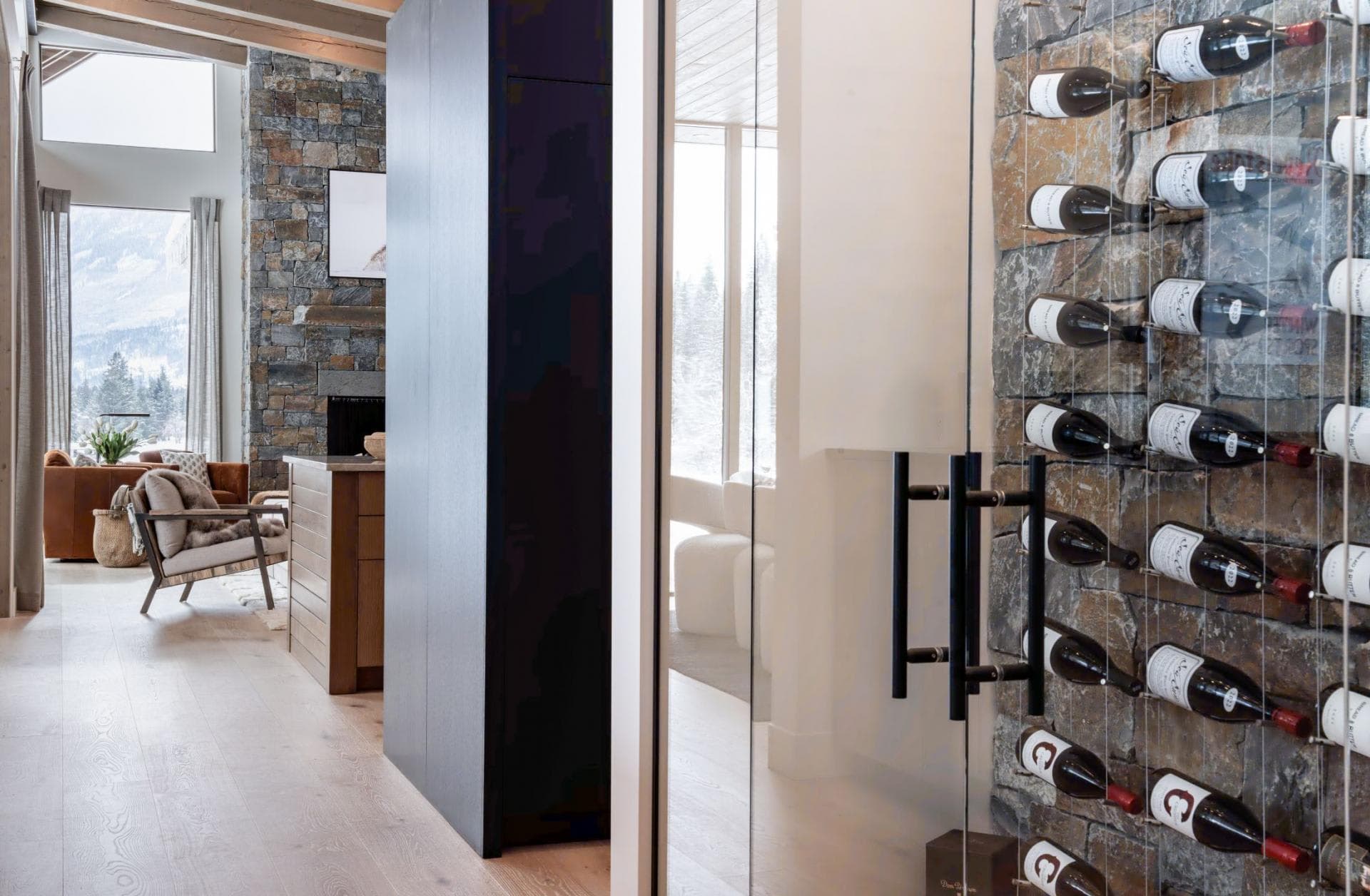 Glass-enclosed wine cellar with stone feature wall and cable racking