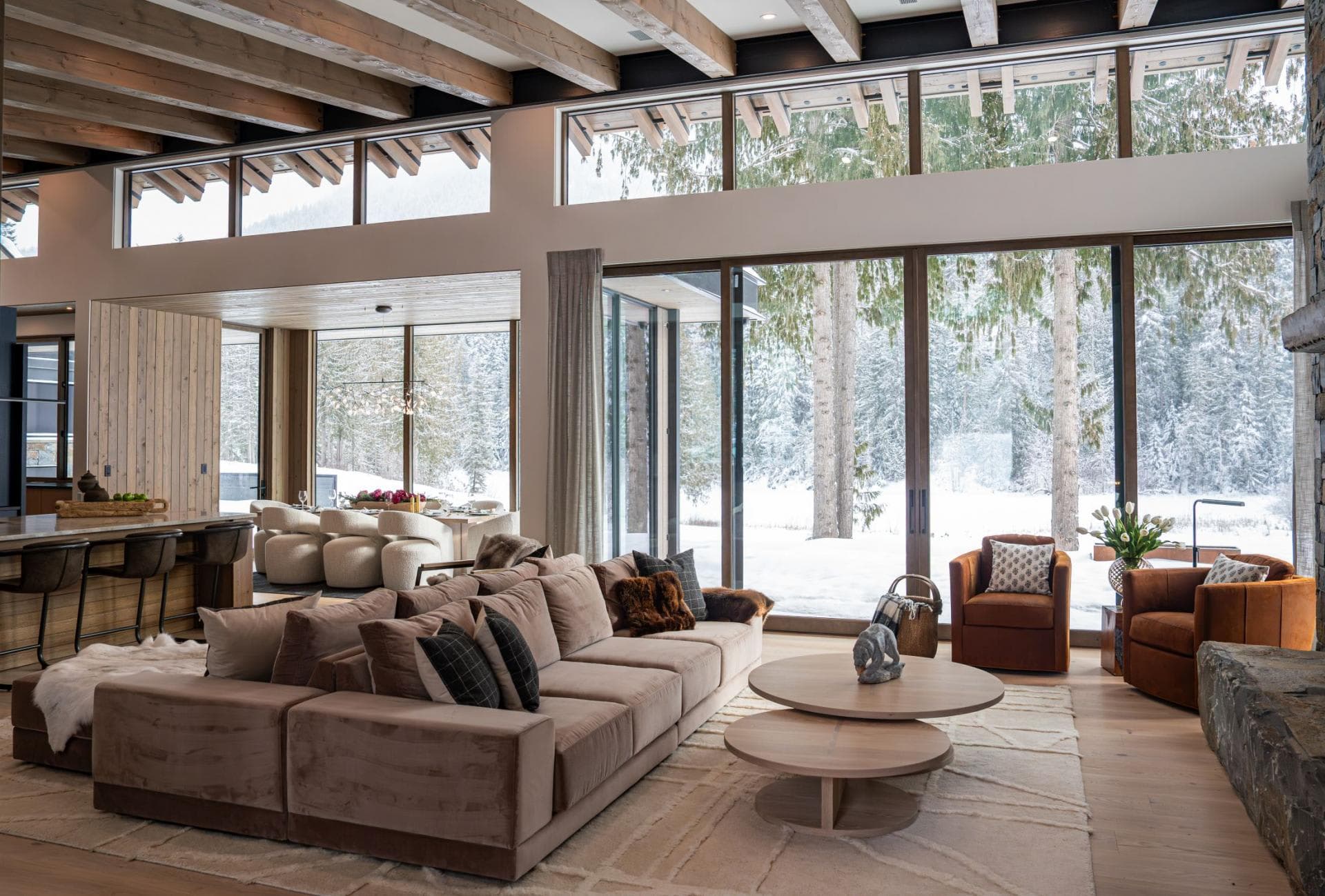 Living room with sectional seating and floor-to-ceiling forest views