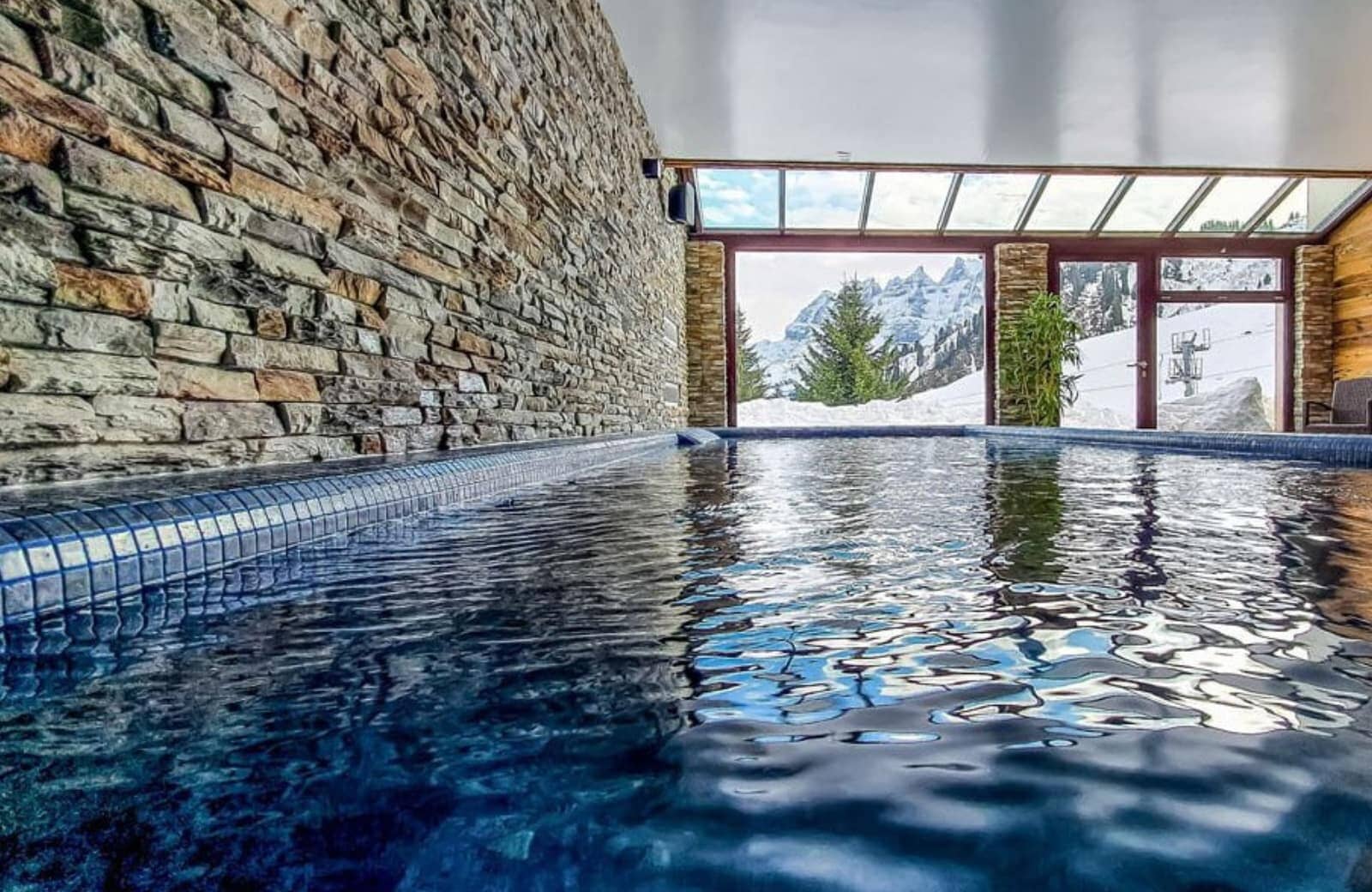 Indoor heated pool with stone wall and mountain views