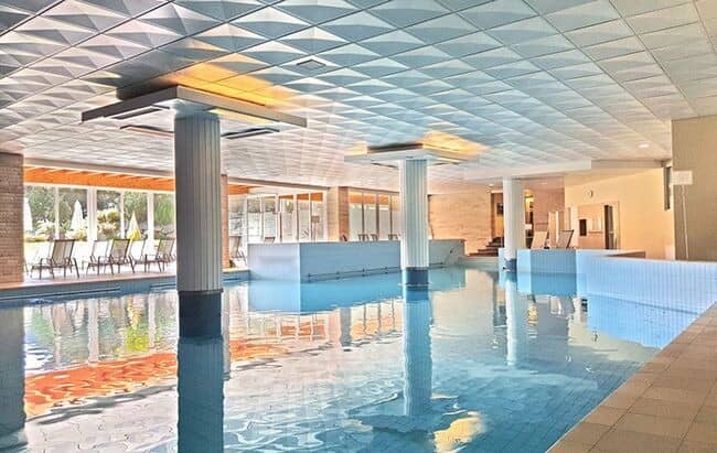 Indoor pool with floor-to-ceiling windows and access to outdoor patio