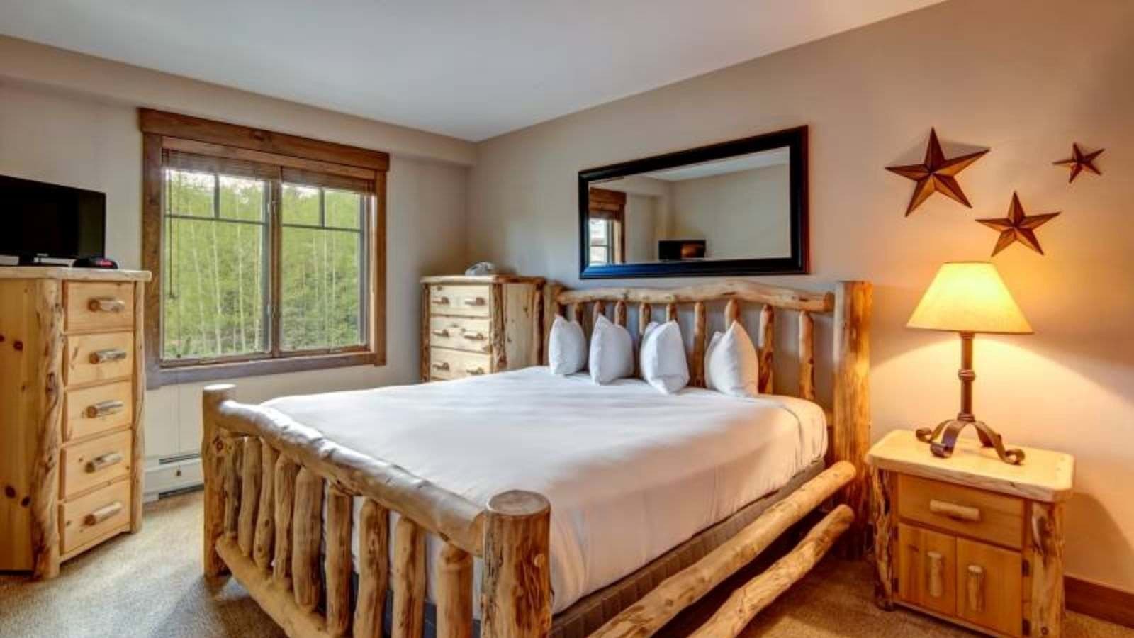 Guest bedroom with log frame queen bed and forest view
