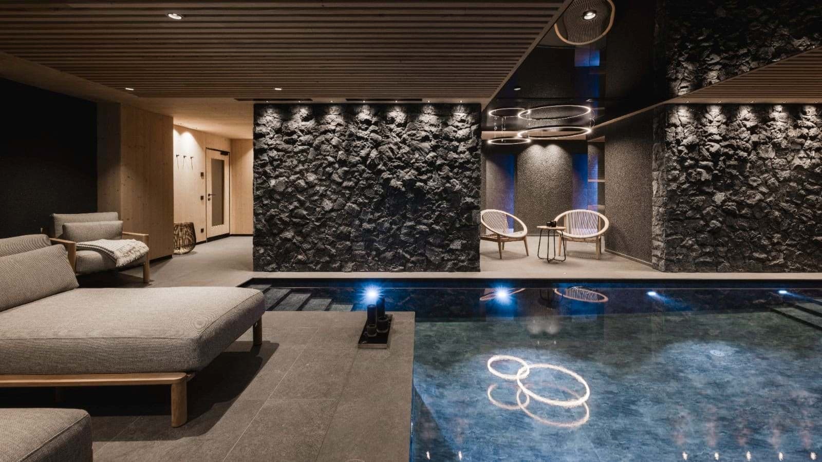 Indoor heated pool with stone feature walls and lounge seating