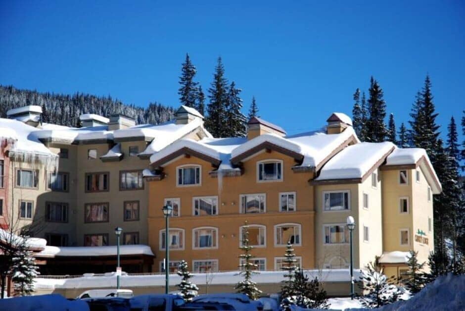 Lodge exterior featuring snow-covered roofs and mountain forest backdrop