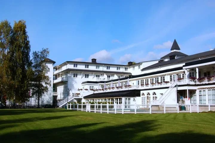 Hotel exterior with manicured lawn and gated outdoor swimming pool