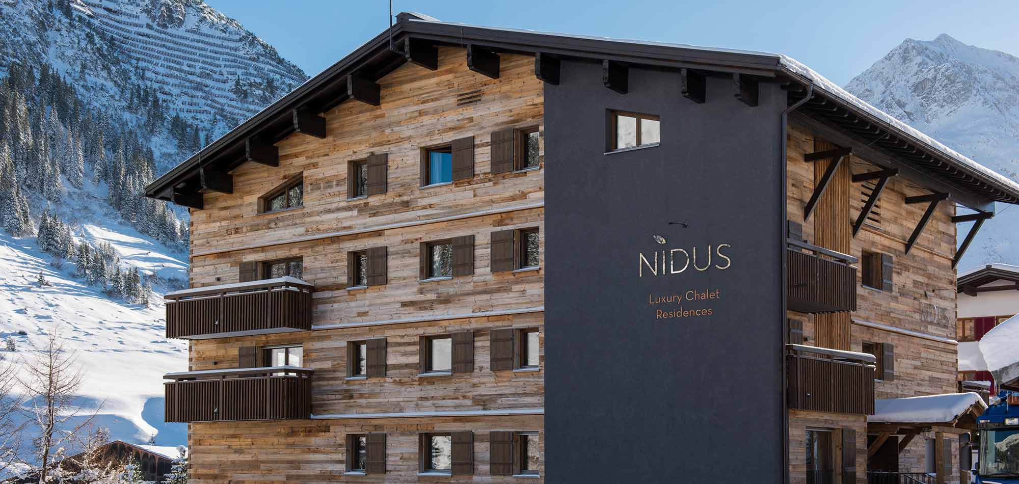 Chalet exterior with timber cladding and private balconies; mountain backdrop