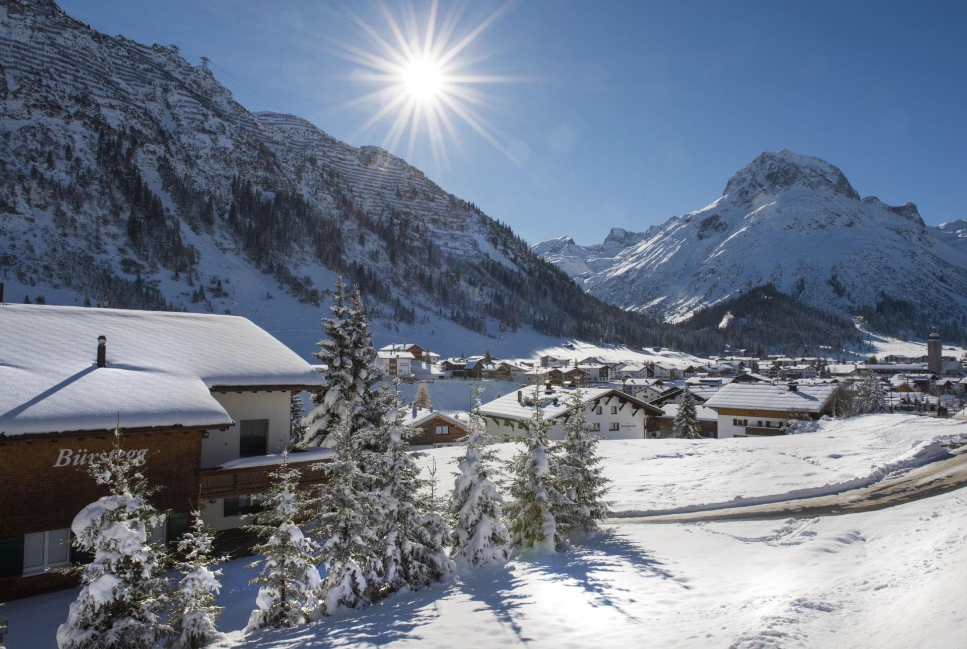 Alpine village valley view; snow-covered peaks and ski slopes backdrop