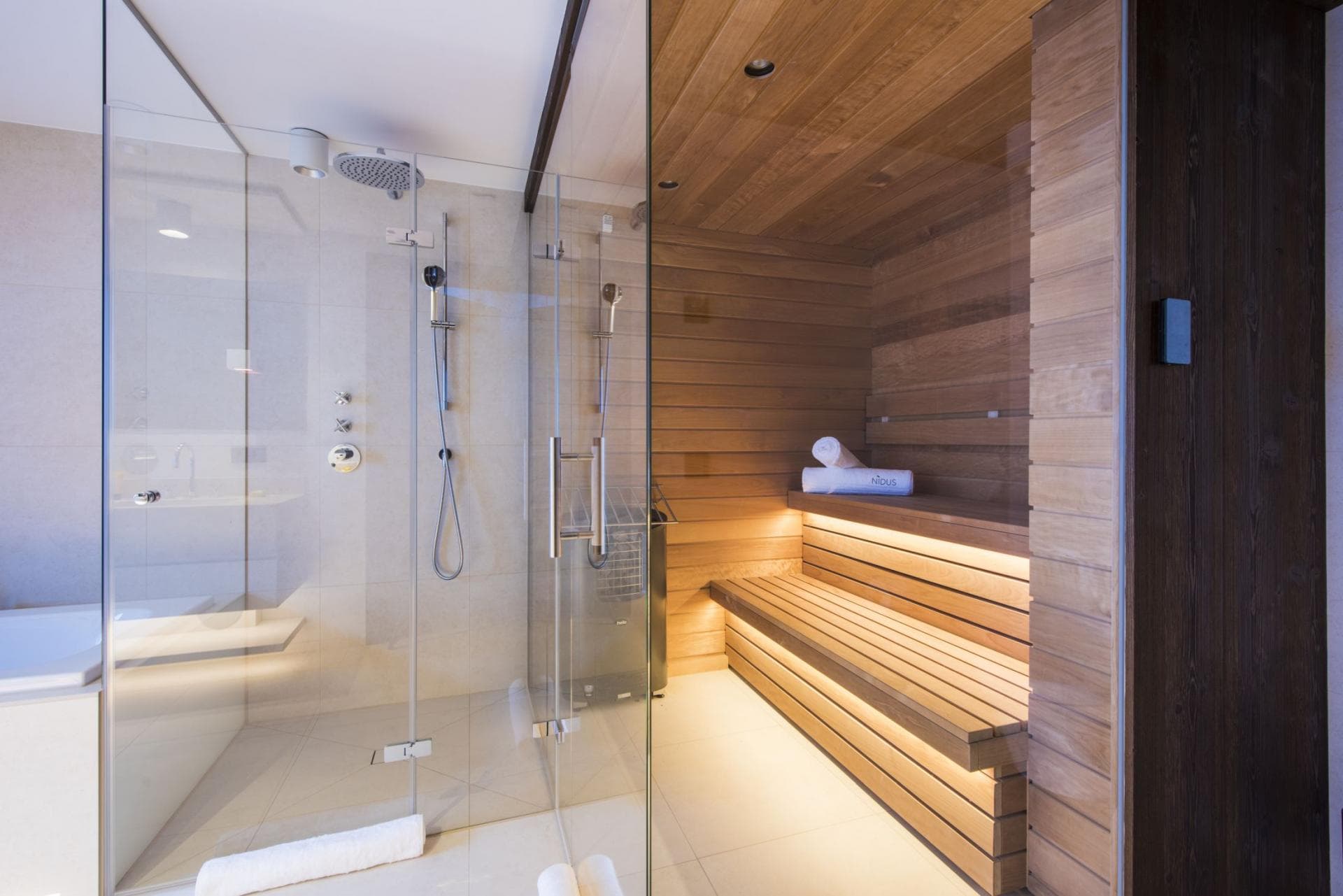 Spa bathroom with walk-in shower, sauna with heated benches, and ambient lighting