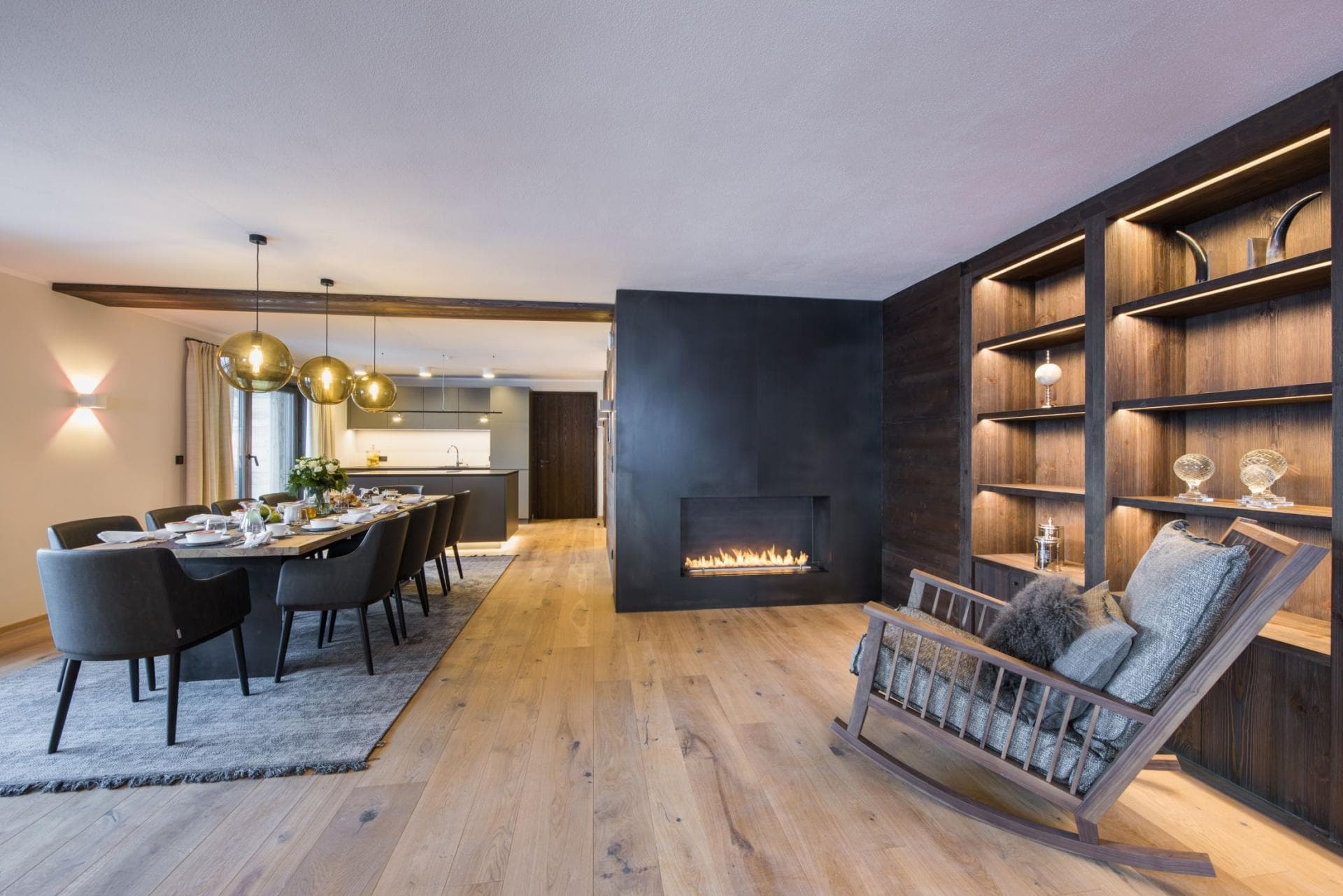 Open-plan living with linear fireplace, built-in shelving, and dining area seating 6