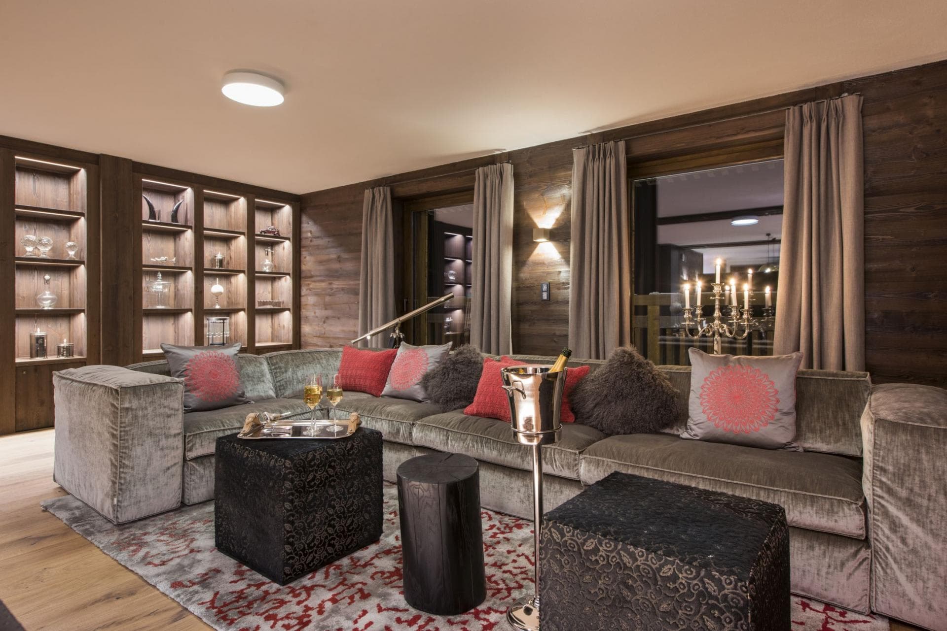 Living area with velvet sectional, brass telescope, and backlit display shelving