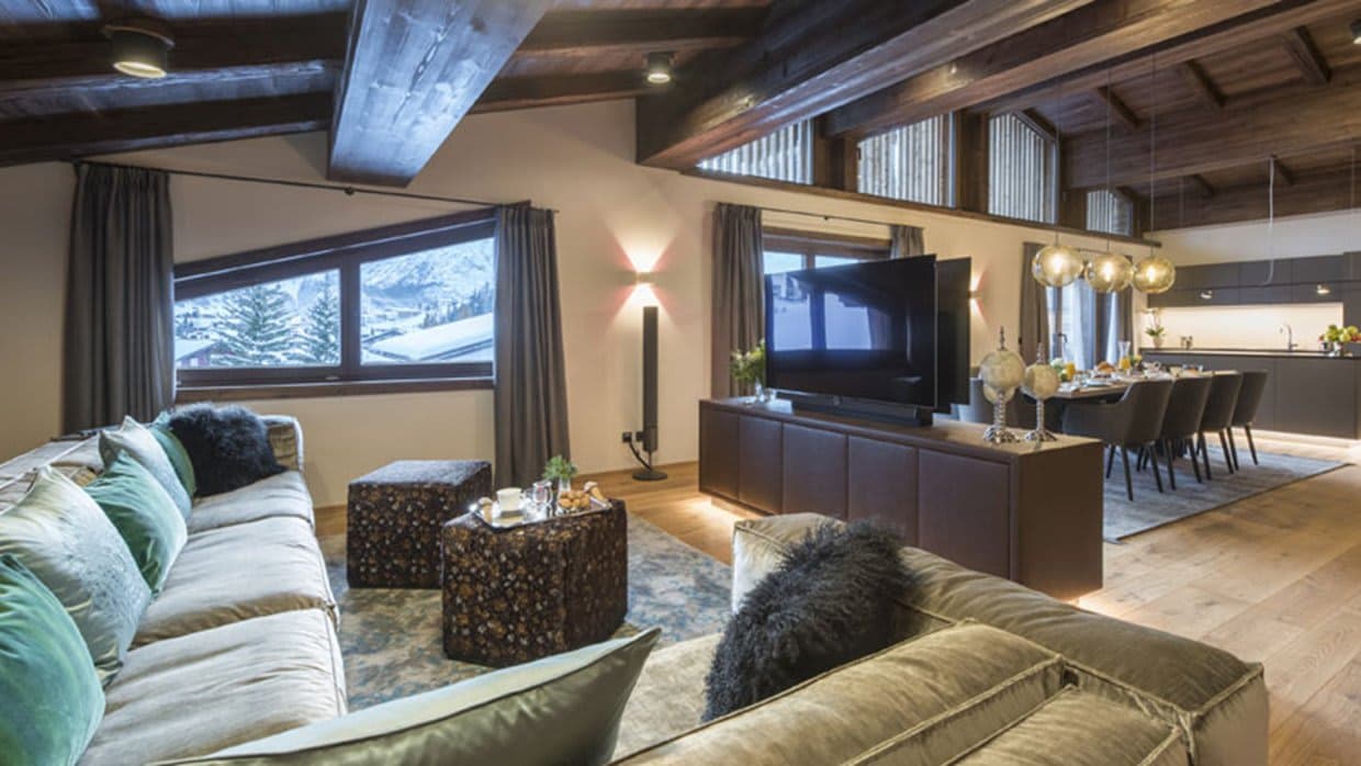 Open-plan living area with vaulted wood ceilings and ski slope views