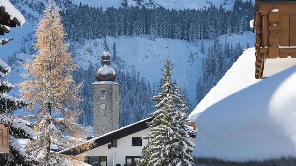 Village view with historic church tower and snow-covered mountain slopes