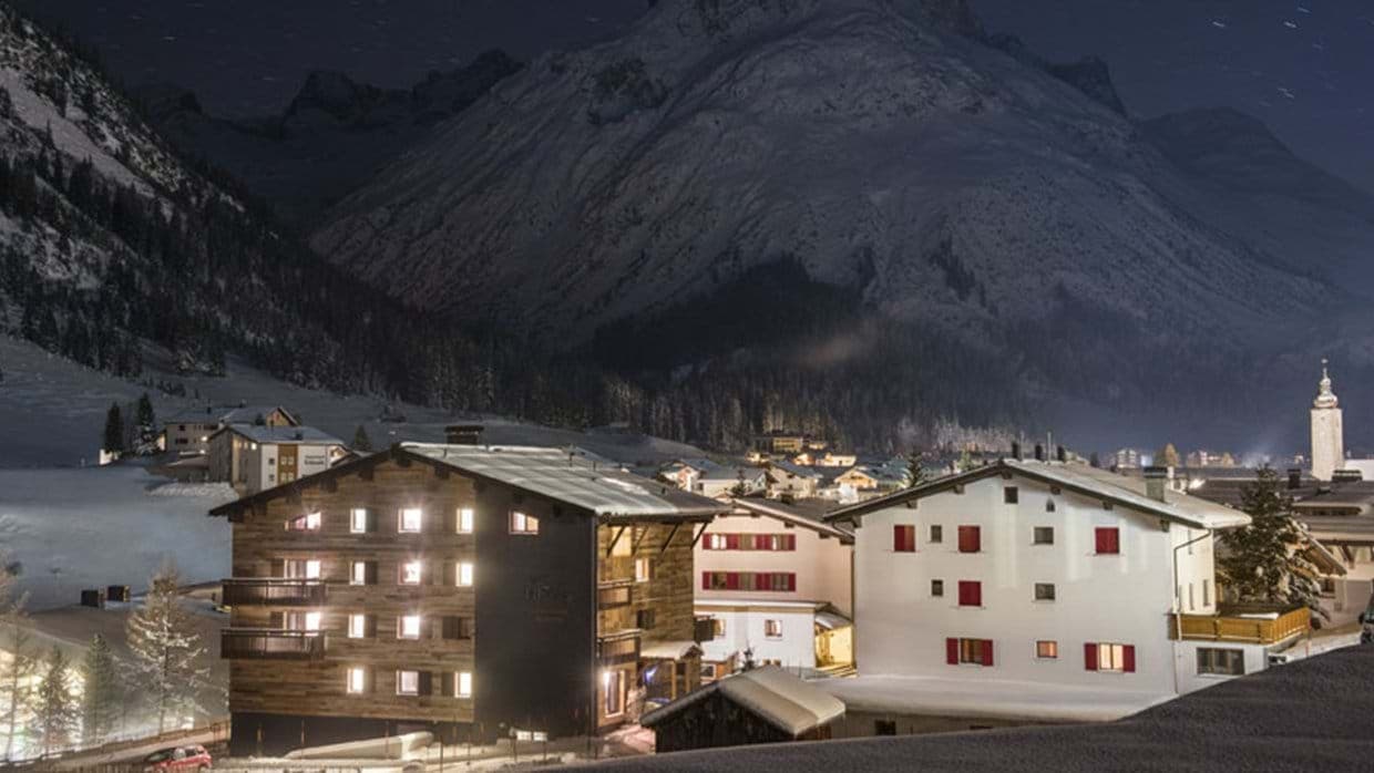 Exterior view at night with village lights and mountain backdrop