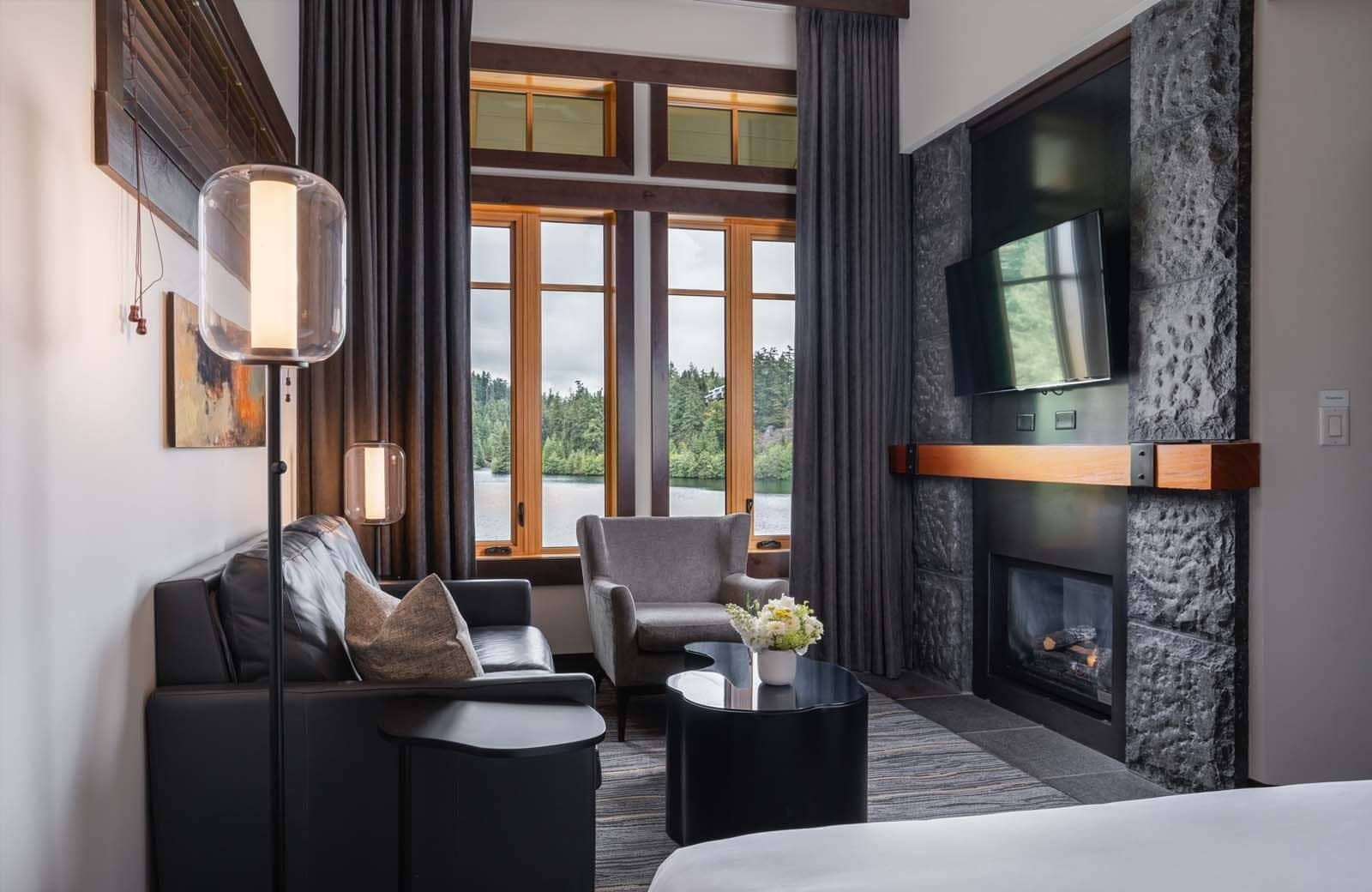 Living area with stone gas fireplace and forest lake views