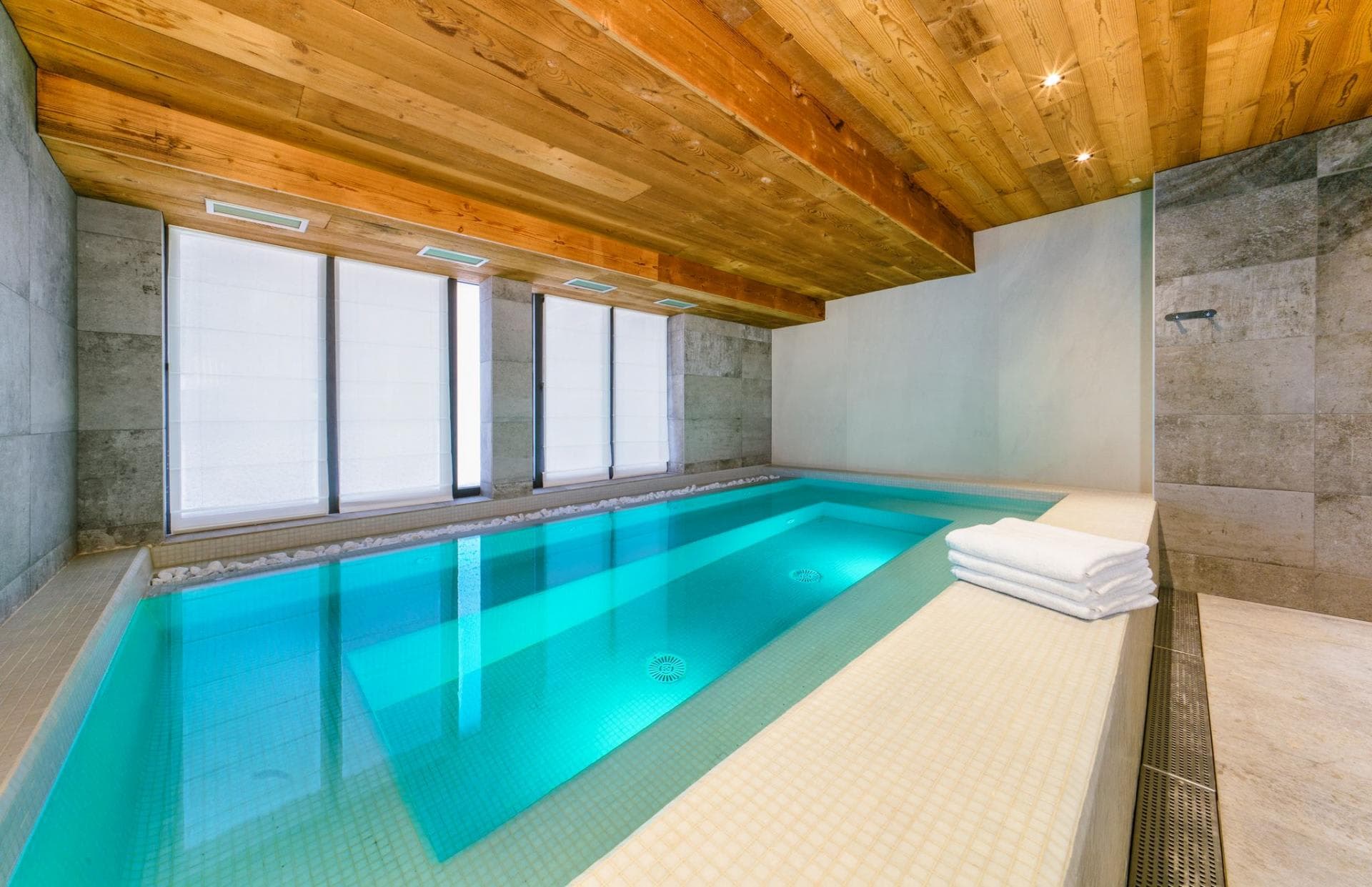 Indoor heated lap pool with timber ceiling and stone tile walls