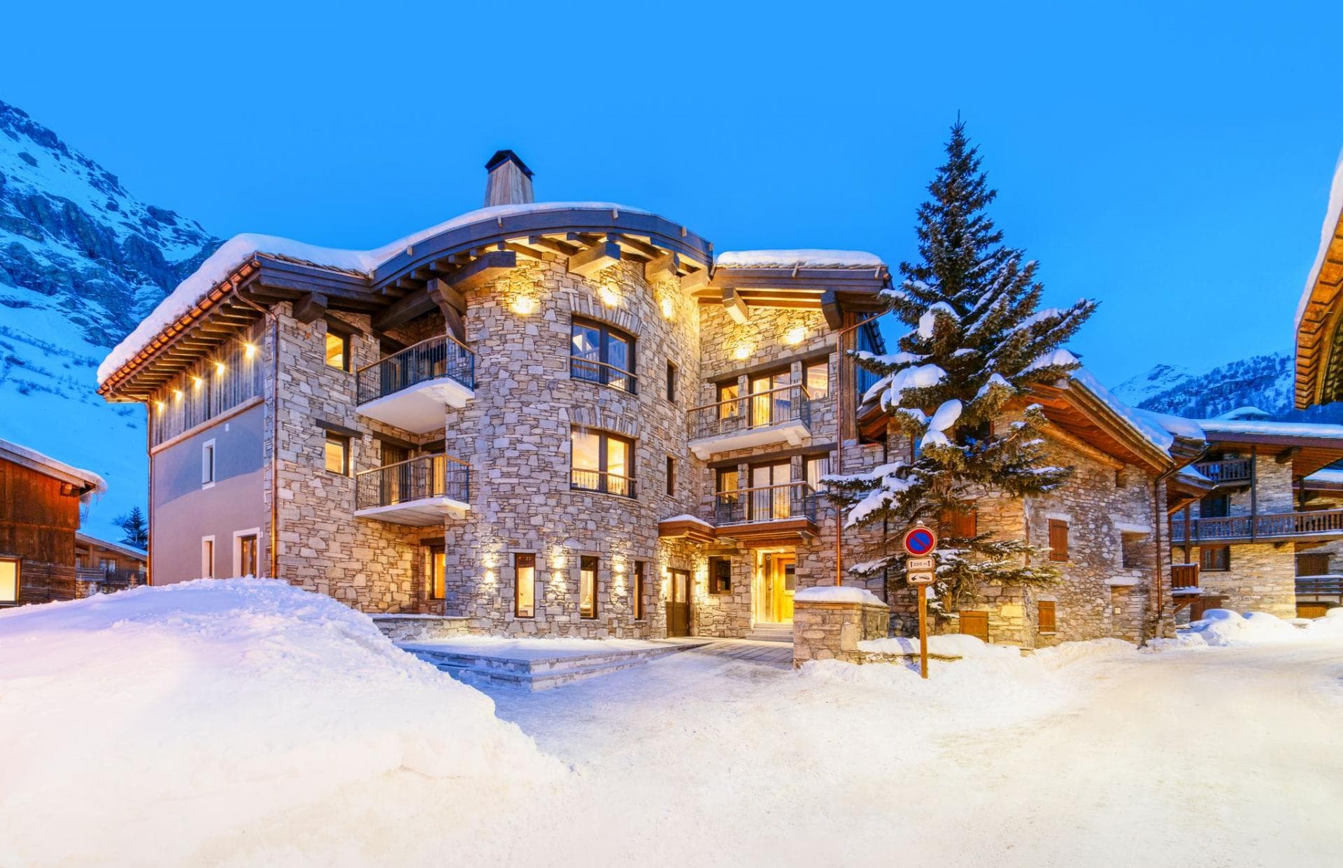 Stone chalet exterior featuring private balconies and snow-cleared driveway access