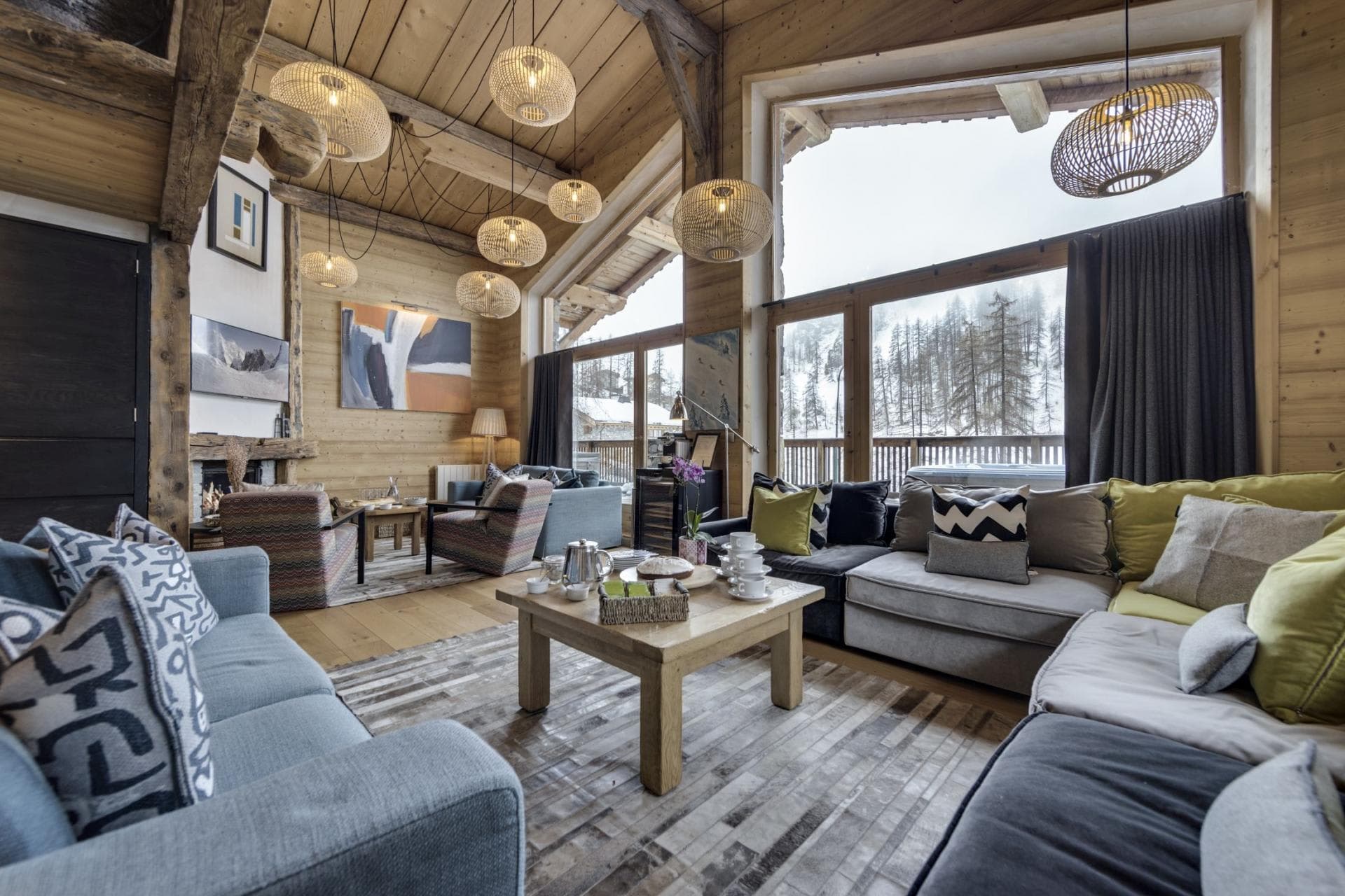 Living area with wood-burning fireplace and floor-to-ceiling forest views