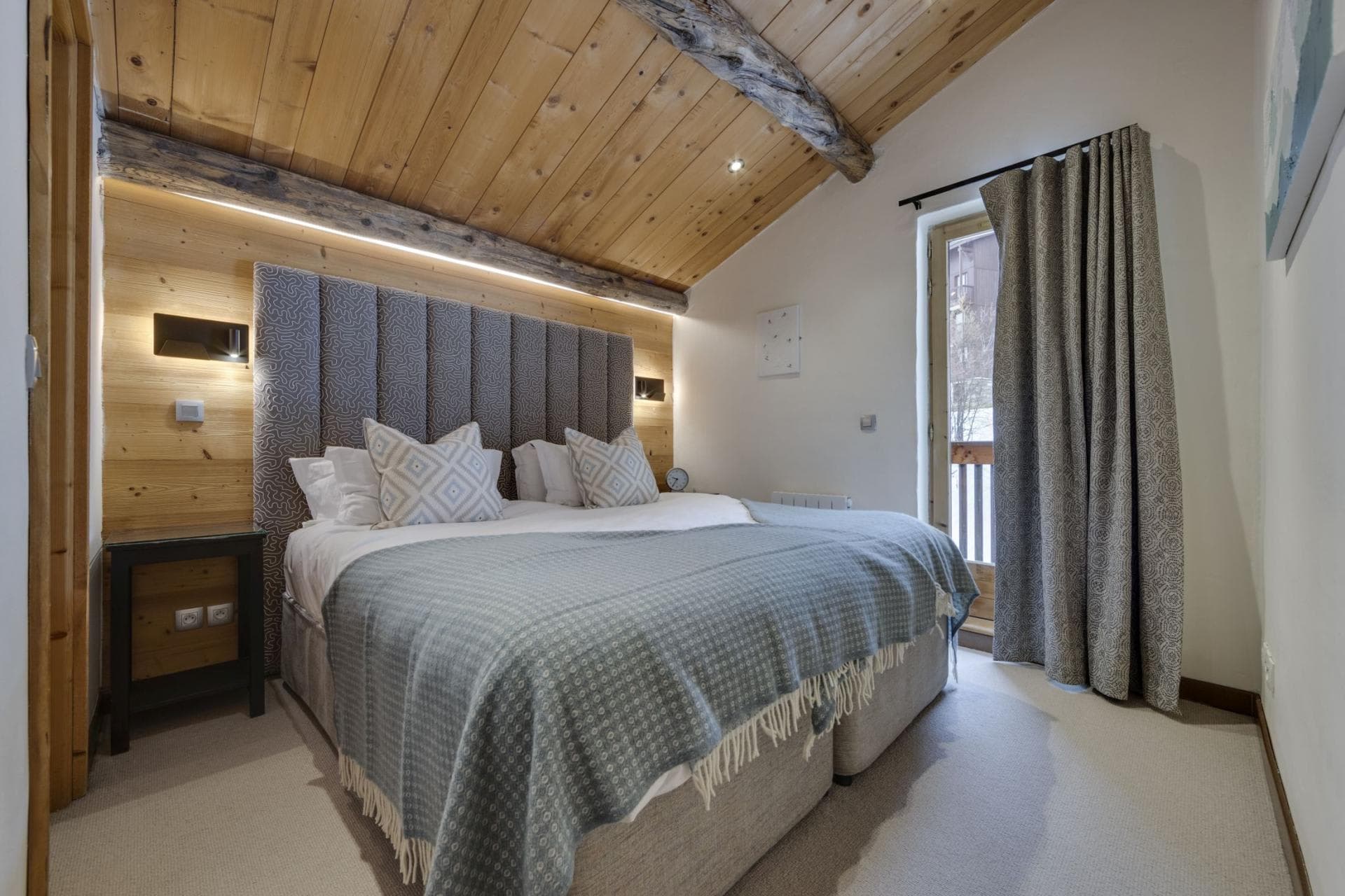 Guest bedroom with king bed, vaulted wood ceiling, and balcony access