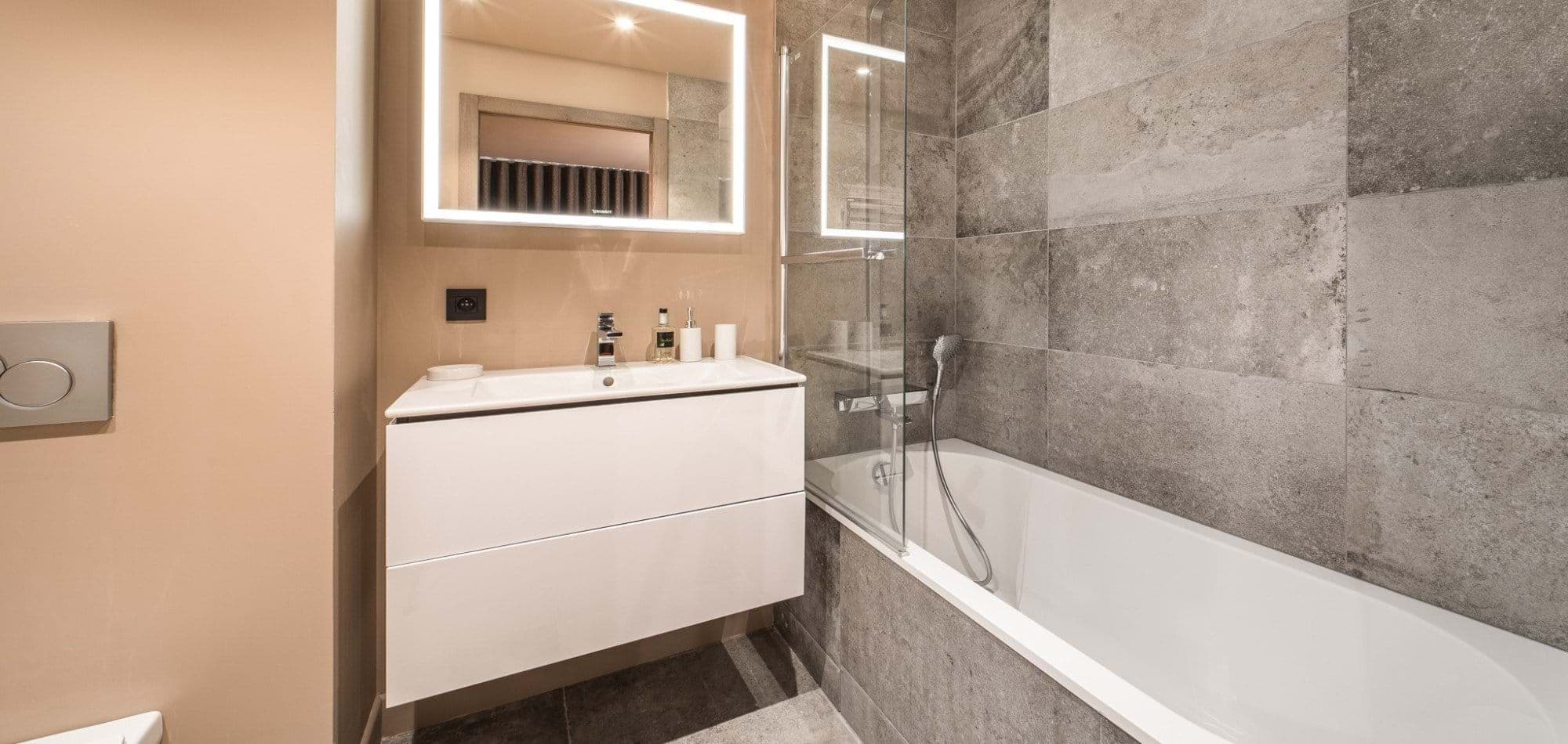 Bathroom with backlit LED mirror and floating vanity; bathtub with glass screen