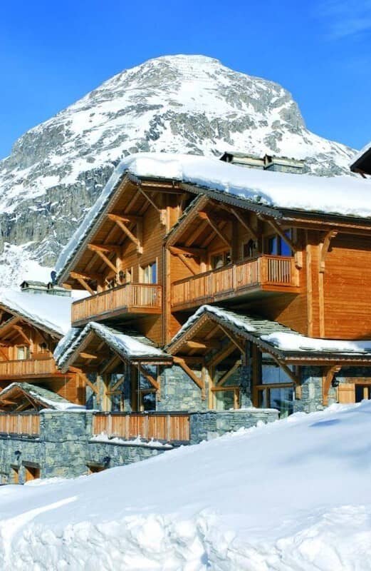 Timber and stone chalet with private balconies; mountain backdrop
