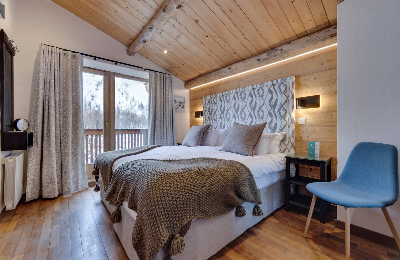Bedroom with vaulted wood ceiling and balcony access to mountain views