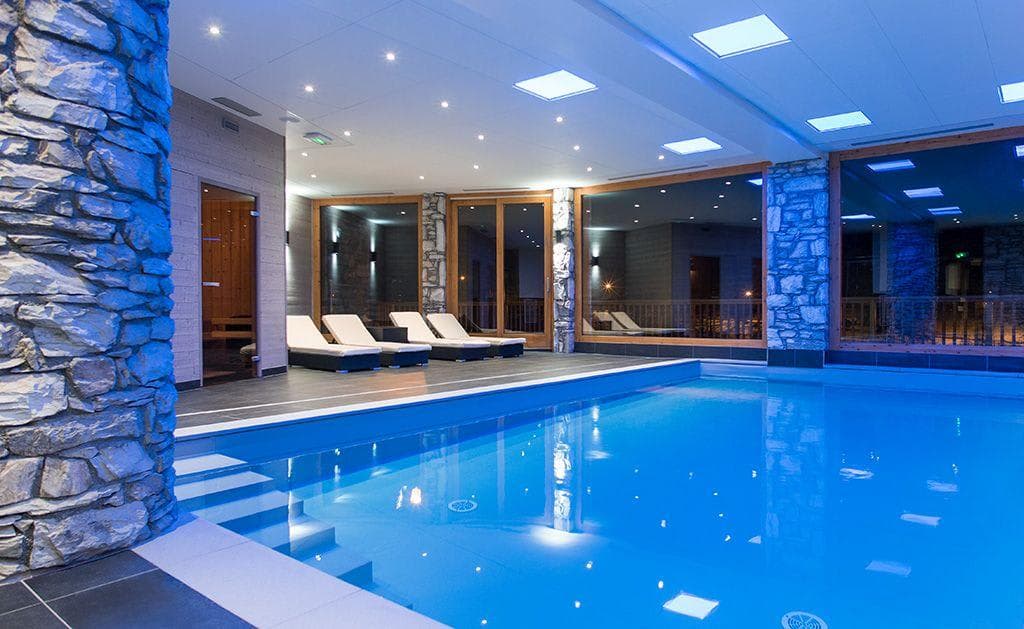 Indoor pool with loungers and adjacent glass-door sauna