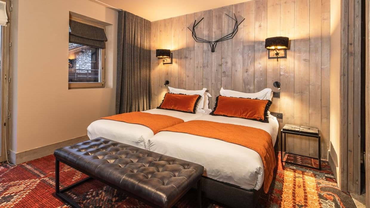 Guest bedroom with two twin beds and wood-paneled feature wall