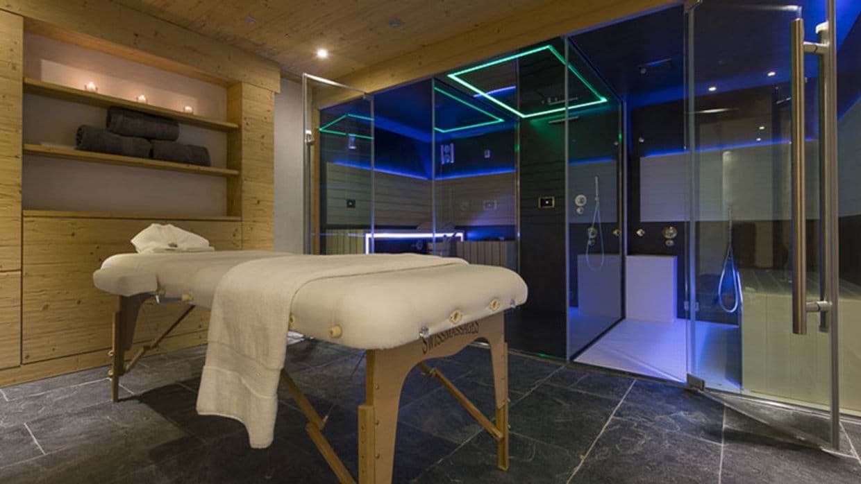 Private spa room with massage table, steam shower, and sauna