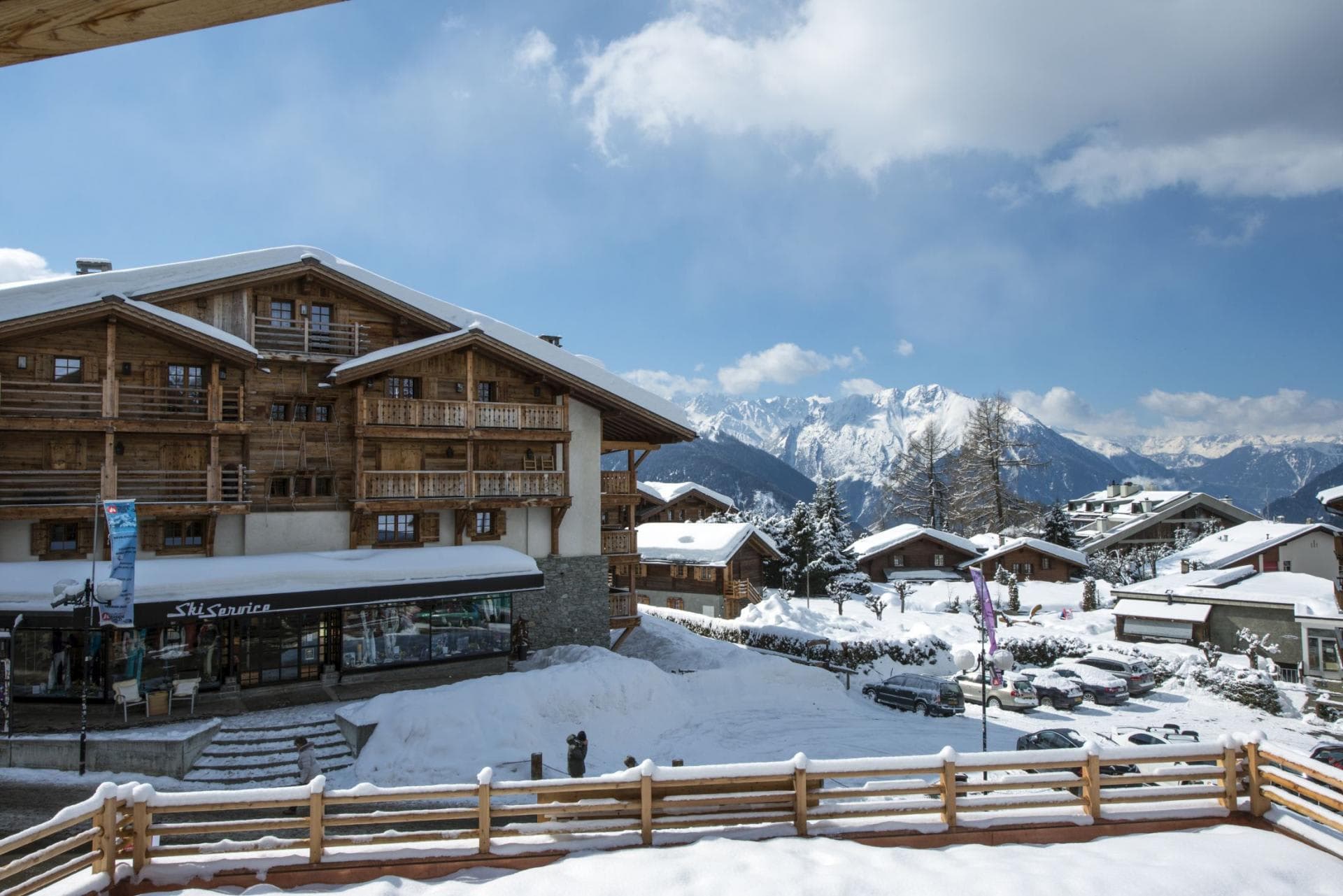 Terrace view of alpine village, mountain peaks, and nearby ski shop