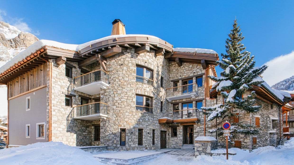 Stone-clad chalet exterior with private balconies and mountain views
