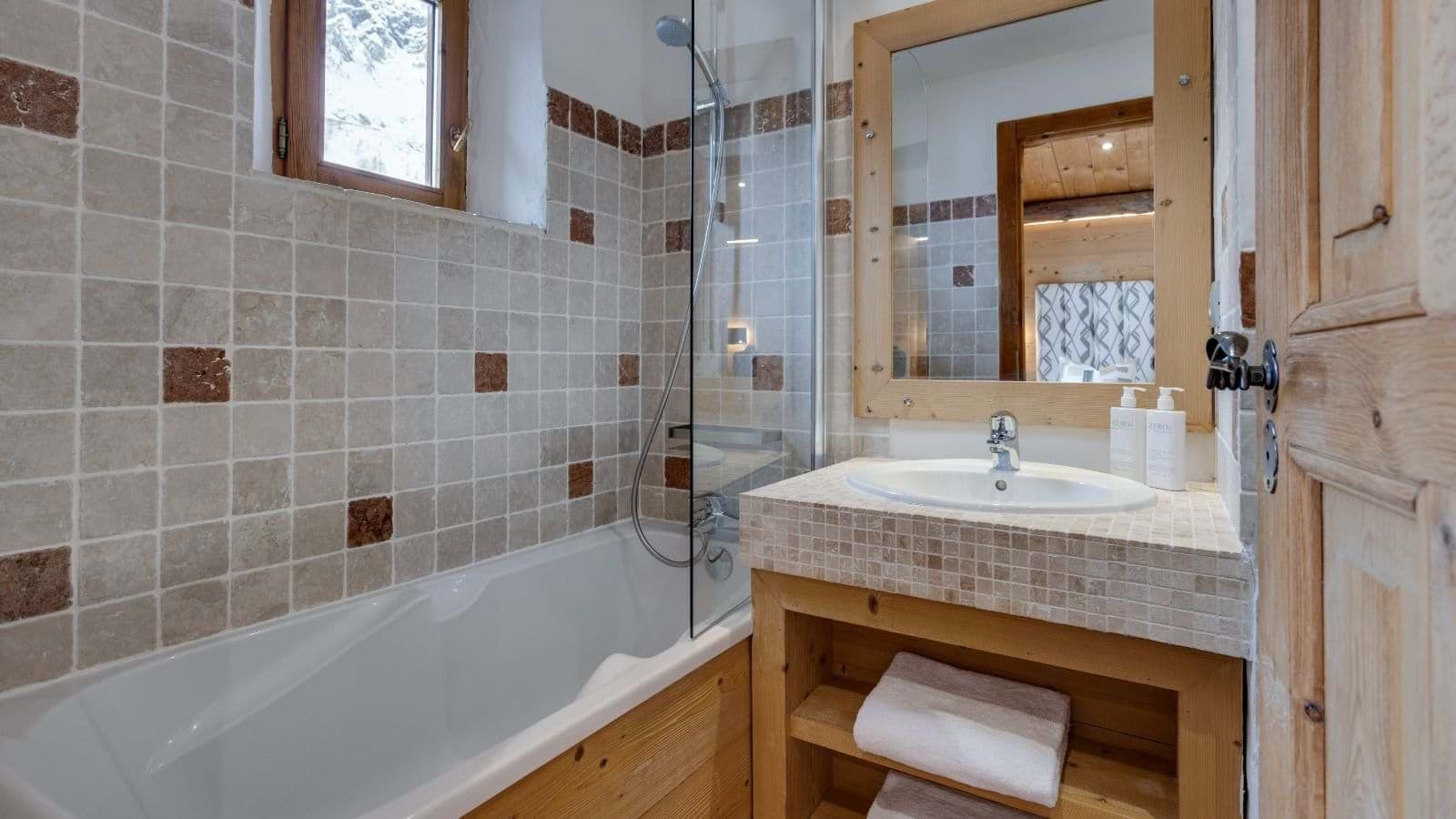 Bathroom with bathtub, rainfall showerhead, and rustic stone tile