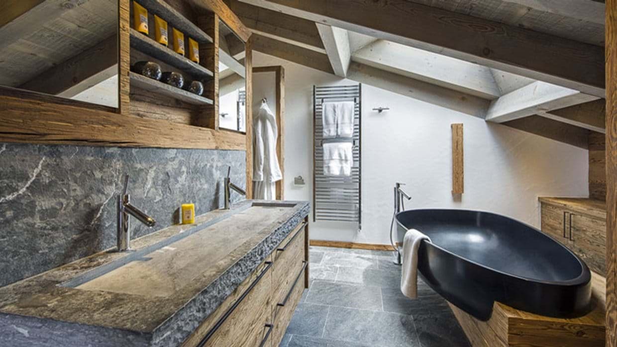 Bathroom with double stone trough sink, soaking tub, and heated towel rack
