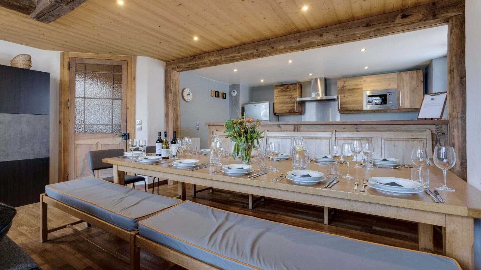 Dining table seats 11 with padded bench seating and kitchen view