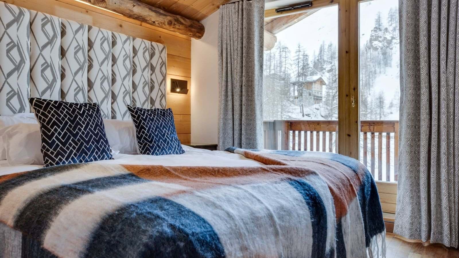 Bedroom with king bed and balcony overlooking snowy forest