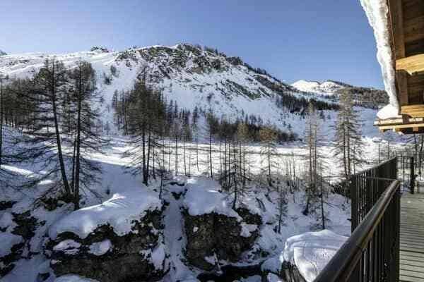 Balcony overlooking snowy mountain peaks and pine forest