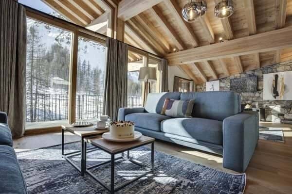 Living area featuring vaulted timber ceilings and snowy mountain views
