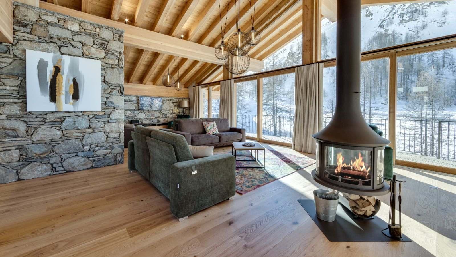 Living area with wood-burning fireplace and floor-to-ceiling mountain views
