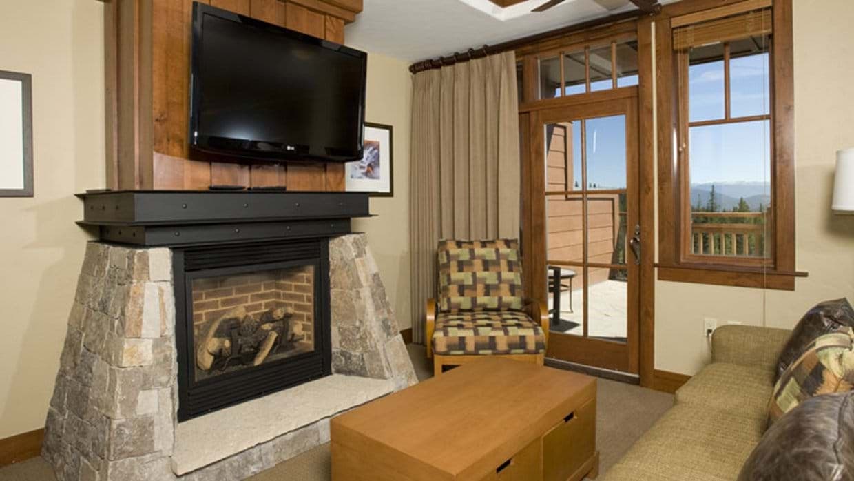 Living area with stone gas fireplace and private balcony access