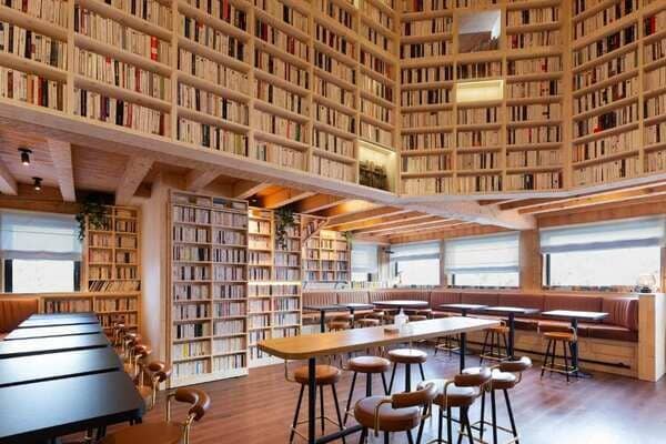 Library lounge with communal tables and floor-to-ceiling bookshelves