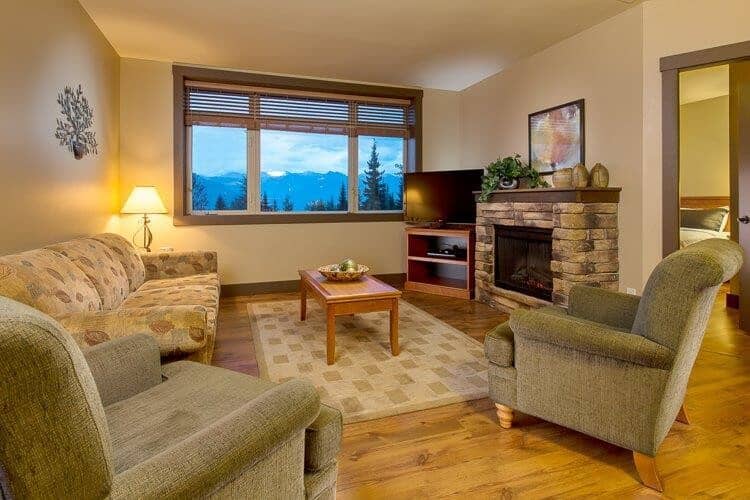 Living area with stone fireplace and mountain views through wide window