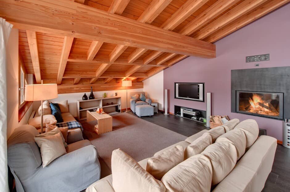 Living area with wood-beamed ceiling, wood-burning fireplace, and media center